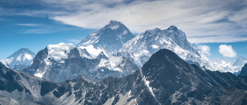 Snow covered mountains against a blue and cloudy sky